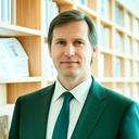Portrait of Carlos Vega standing beside bookshelves in a bright legal library
